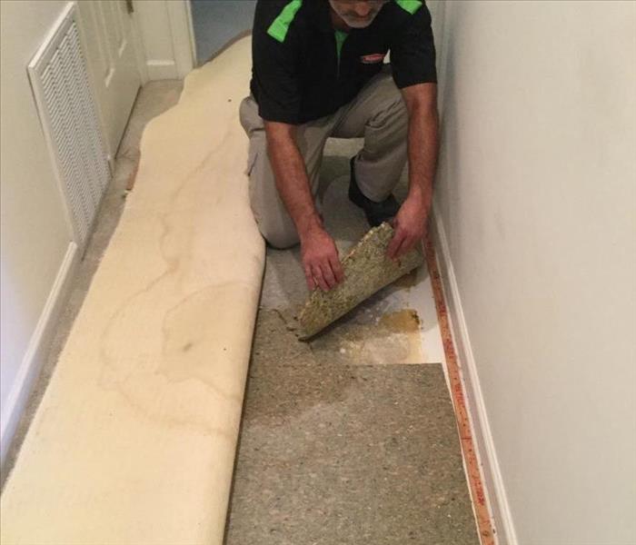 narrow hallway with Servpro employee removing wet insulation 