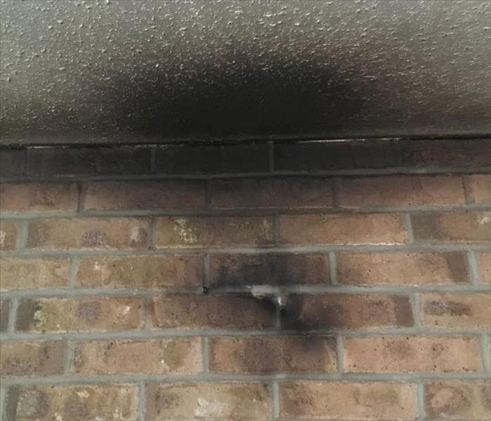 ceiling of a brick wall with heavy smoke and soot damage 