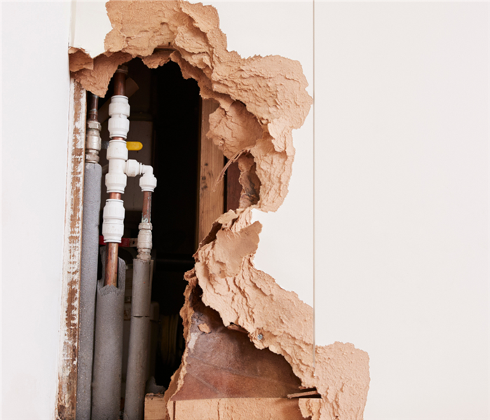 hole in wall exposing pipes