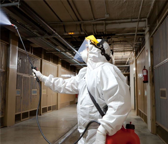 A person in PPE spraying for COVID
