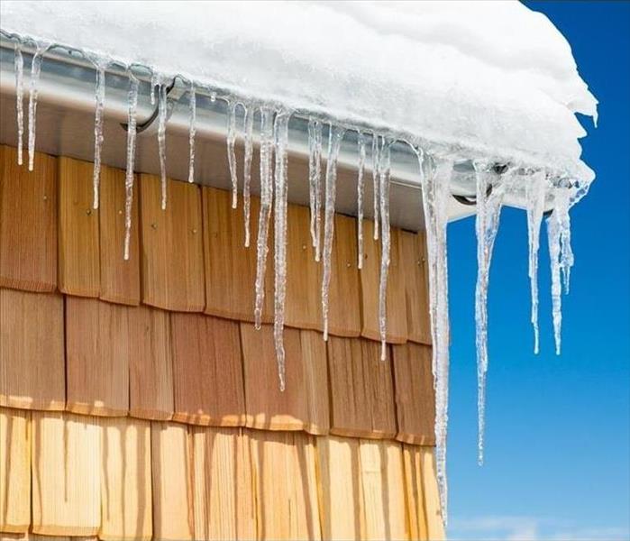 image of gutter of a home completely covered in snow with icicles hanging down