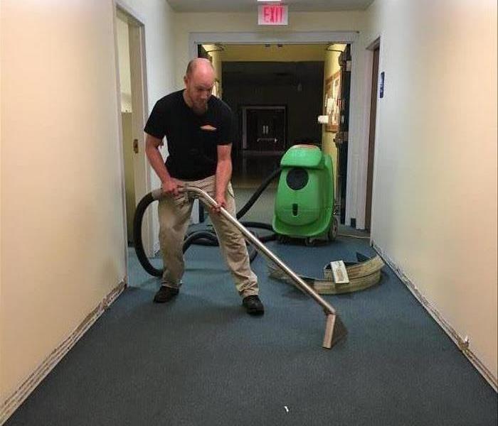 employee in a commercial building hallway holding an extractor 